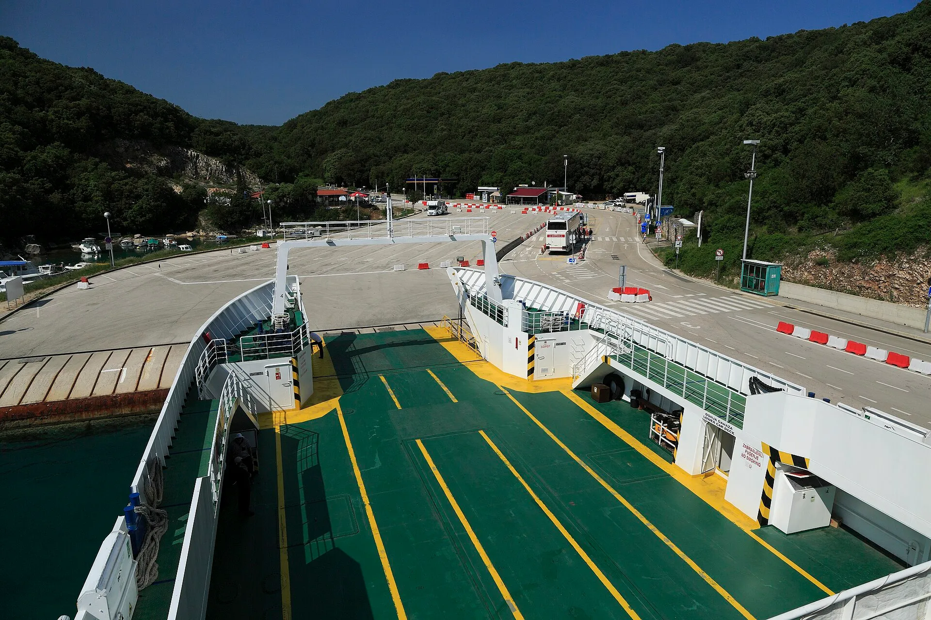 The car deck with yellow lane markings, ramp down onto the marshalling area at the port